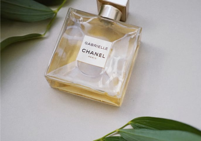 Chanel perfume bottle surrounded by decorative leaves.