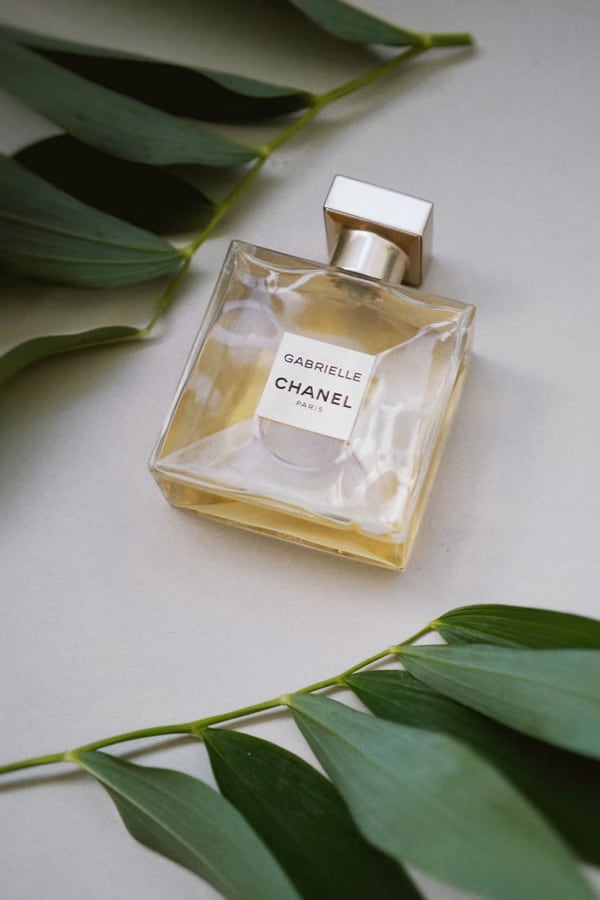 Image of Chanel perfume bottle surrounded by decorative leaves.